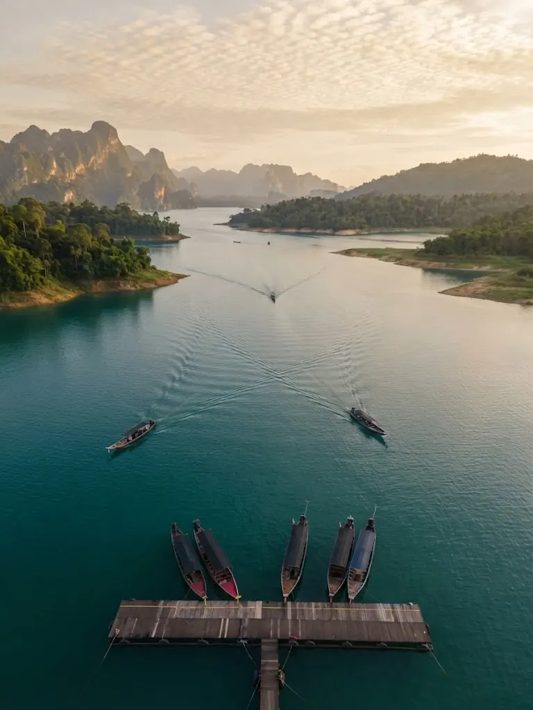 Aerial view of long-tail boats leaving a jetty on the lake at dawn