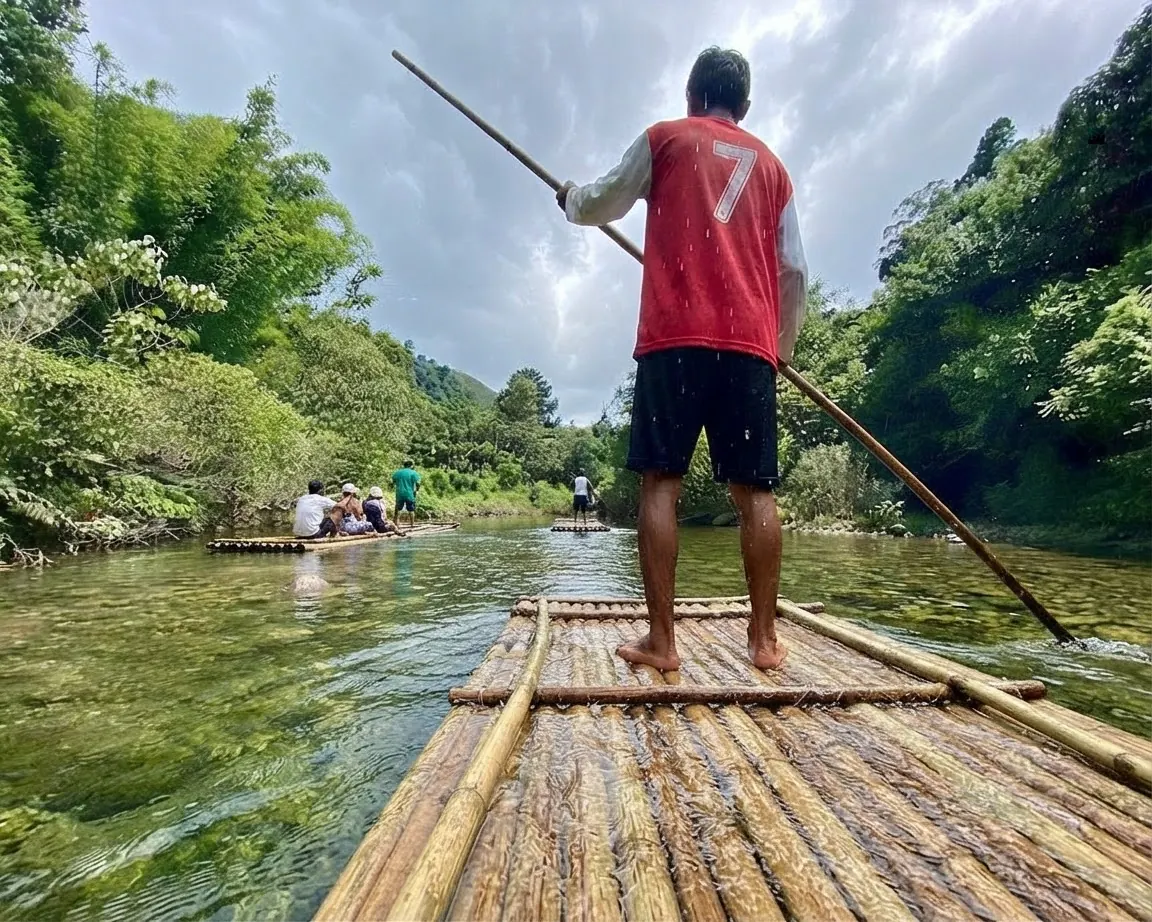 Boatman poling a bamboo raft along a clear jungle river