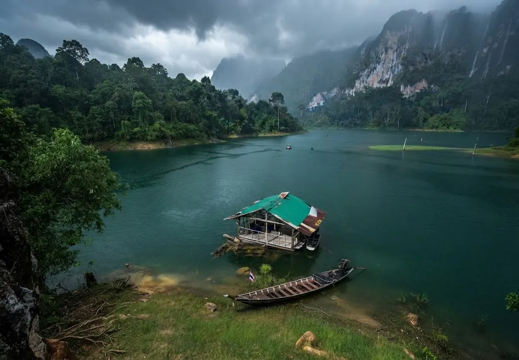 Small floating raft and a long-tail boat in a lake cove under storm clouds