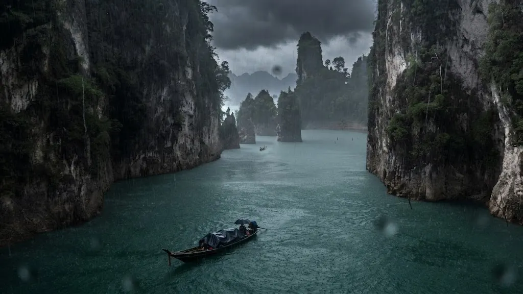 Long-tail boat crossing between limestone cliffs on a rainy day