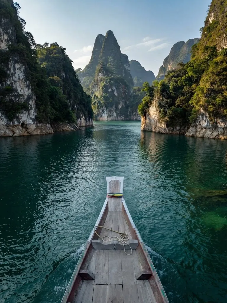 Long-tail boat bow in a narrow lake channel between limestone walls