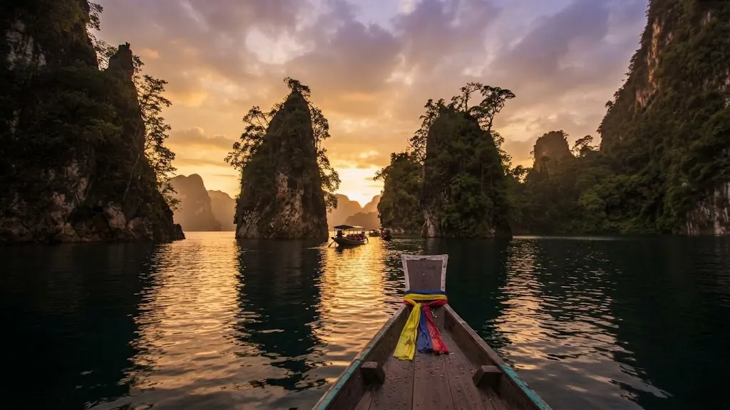 Ribbon-wrapped bow of a long-tail boat facing karst pillars at sunset on Cheow Lan Lake