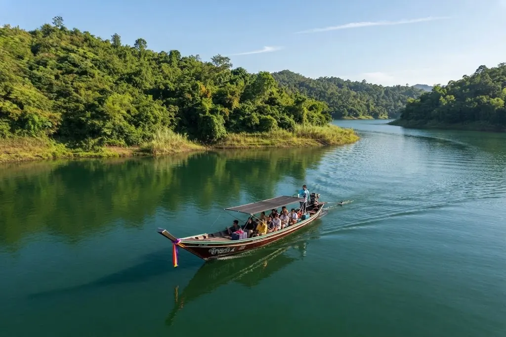 Long-tail boat with passengers crossing a calm lake arm with green shores