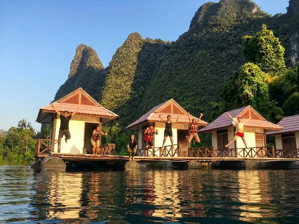 Travellers waving and jumping on floating bungalows at golden hour
